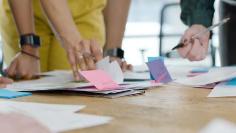 Mid-Section-Of-Colleagues-Working-On-Project-At-Table